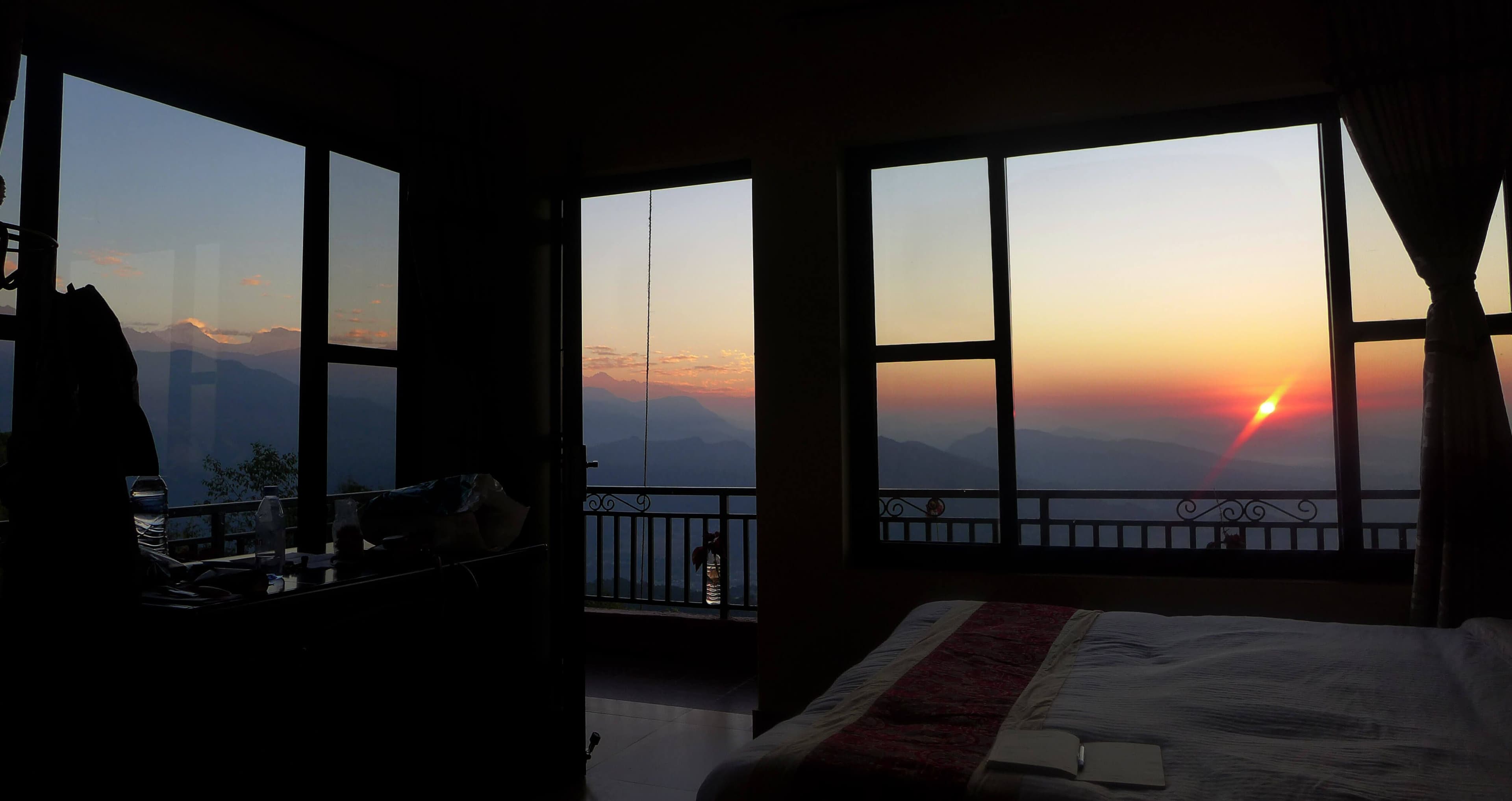 picture of a guestroom, with view of sun rising in the mountains